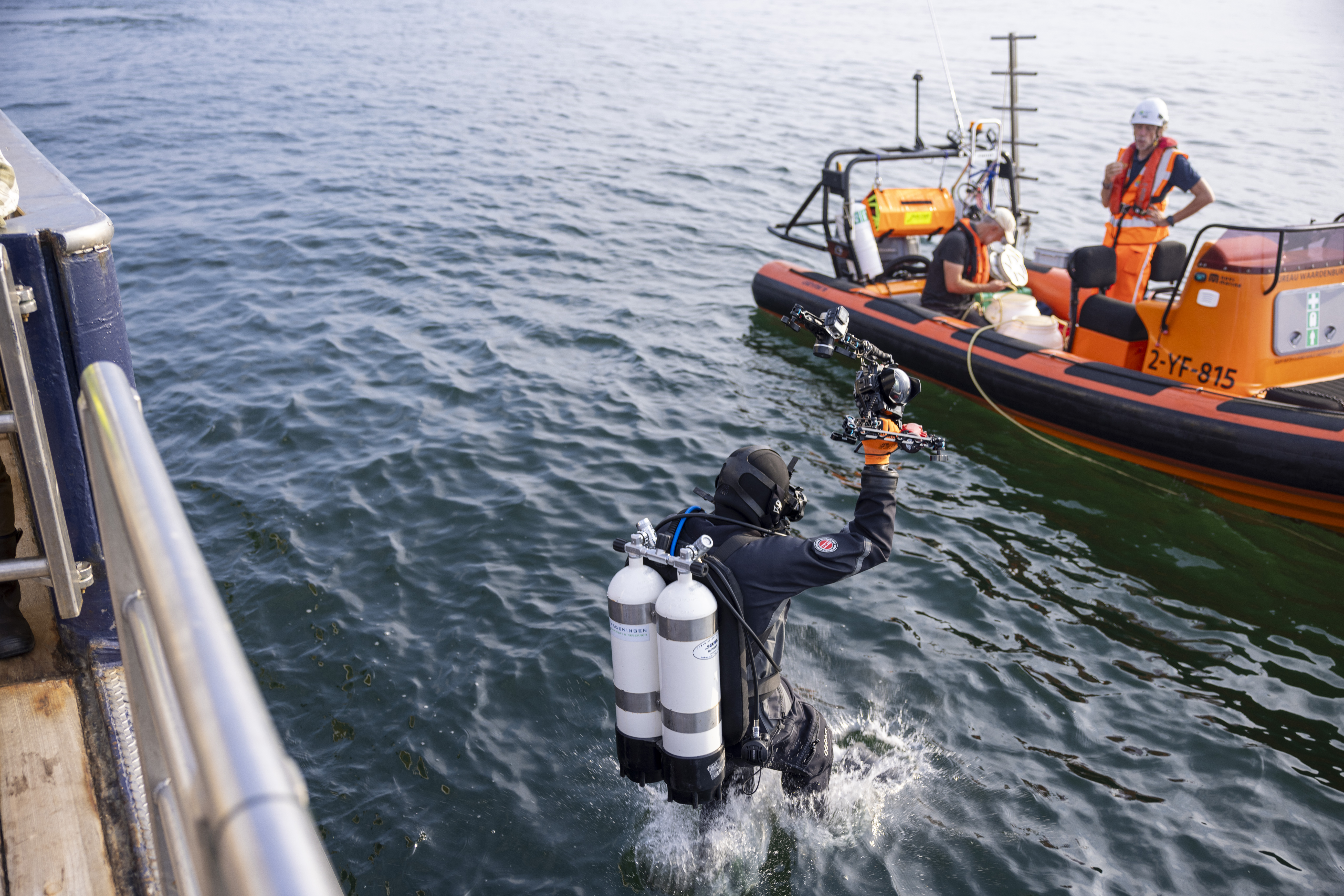 Professionele duikers springen in het water bij de Borkumse Stenen.