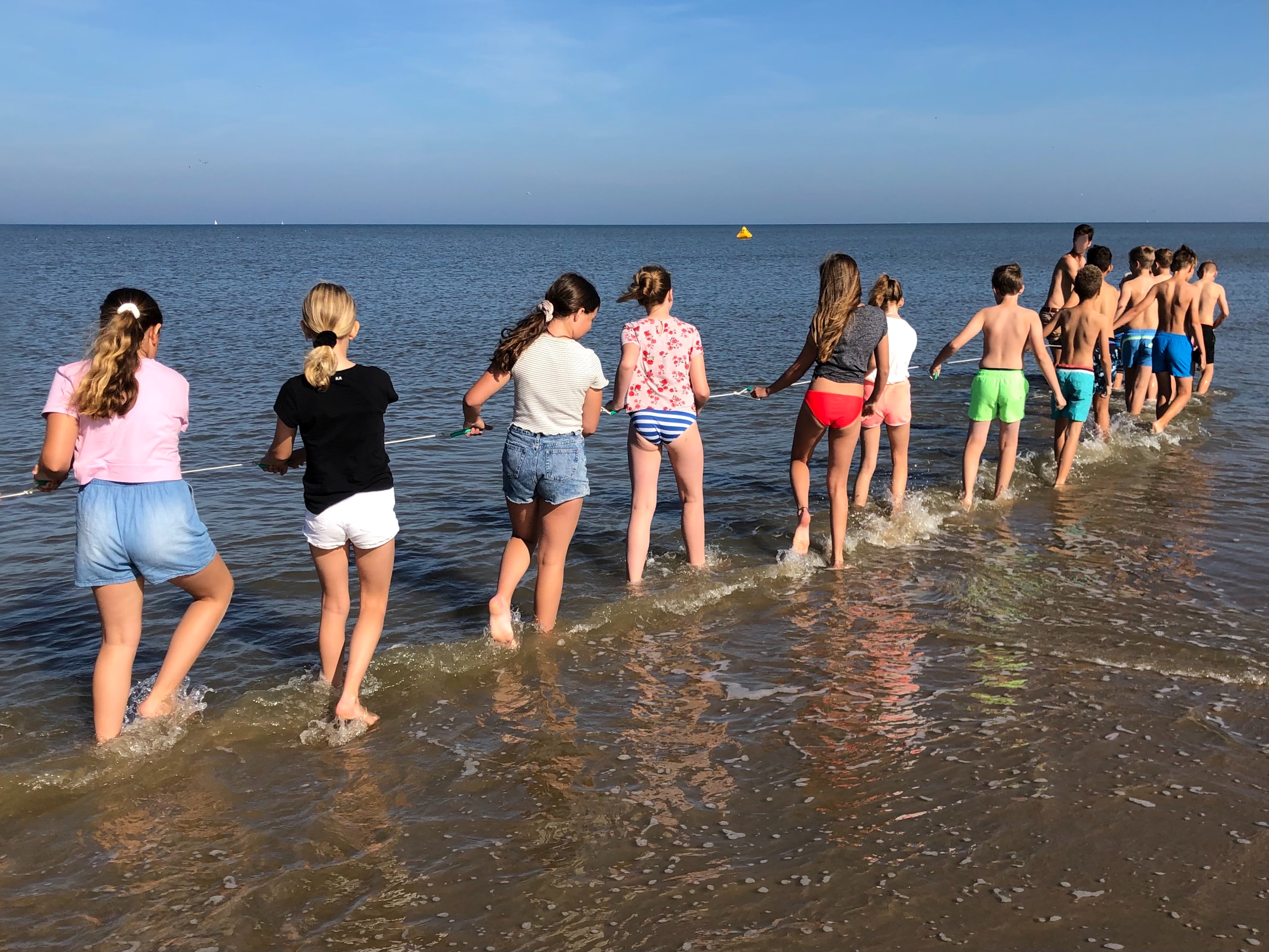 Kinderen lopen door zee met sleepnet